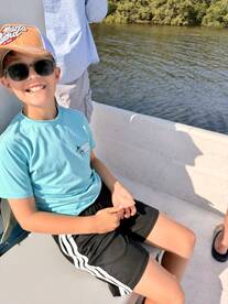 A young angler enjoying a sunny day on a boat, showcasing a relaxed atmosphere while fishing.