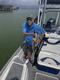 An angler proudly displaying a caught fish while aboard a boat in a coastal fishing environment.