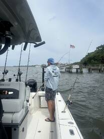 A fisherman casting from a center console boat in a scenic waterway, showcasing a relaxed fishing environment.