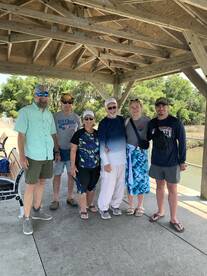 A group of six individuals gathered under a pavilion, likely after a fishing trip, showcasing a friendly atmosphere.
