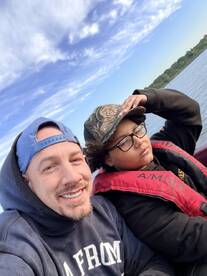 Two individuals enjoying a day on the water, with one wearing a life jacket. The setting appears to be a fishing trip.