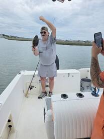 An angler proudly displays a Flounder while fishing on a boat, capturing a memorable moment during a coastal fishing trip.