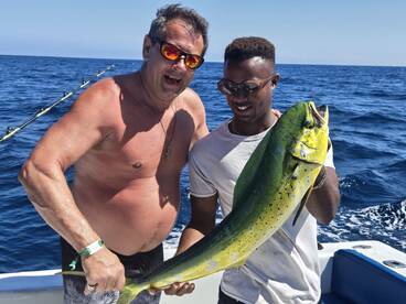 Two anglers proudly displaying a vibrant Mahi Mahi while fishing offshore, showcasing a successful day on the water.