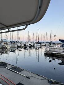 A serene view of a marina at dusk, showcasing various boats and their reflections on the calm water.