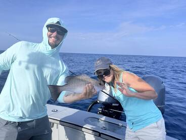 Two anglers proudly displaying a Snapper while enjoying a day out on the open water.