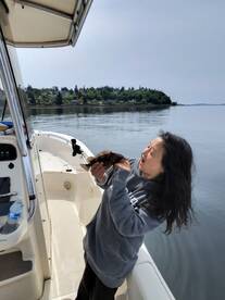 A young angler joyfully holding a freshly caught rockfish on a calm day aboard a fishing boat.