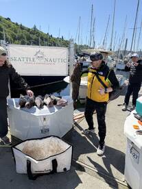 Group of anglers proudly displaying their catch of the day, featuring a large Lingcod and several smaller fish at the marina.