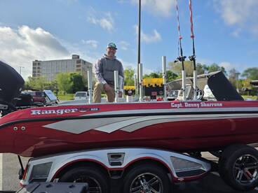 A Ranger FS 622 boat featuring Captain Denny Sharrone, showcasing its sleek design and fishing equipment in a parking area.