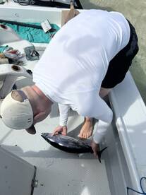 An angler is actively handling a freshly caught fish on the deck of a boat, showcasing the excitement of the fishing experience.