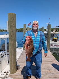 An angler proudly displaying a large Grouper at the dock, showcasing a successful fishing trip.