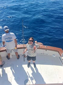Young angler proudly displaying a caught fish while fishing on a charter boat in open waters.