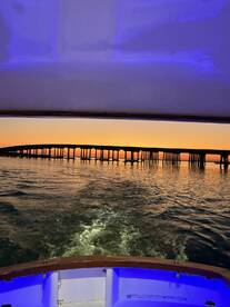 A scenic view from the boat showcasing a pier at sunset, with vibrant colors reflecting on the water.