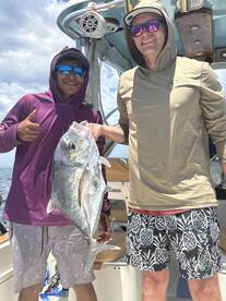 Two anglers proudly displaying a large fish on a boat during a fishing trip.