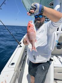 Angler proudly displaying a freshly caught Red Snapper while fishing offshore.