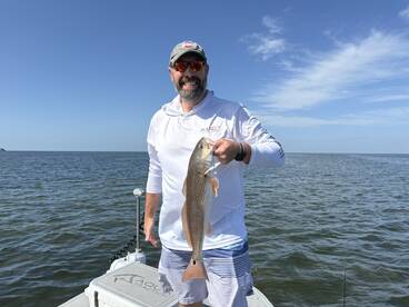 Angler proudly displaying a Redfish while fishing on a sunny day.