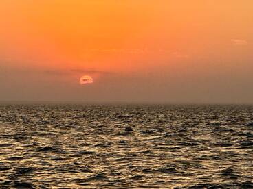 A serene sunset over the ocean, creating a beautiful backdrop for a fishing trip.