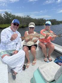 Three anglers proudly displaying their catch of Redfish while enjoying a day on the water.