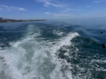 A scenic view of the ocean with boat wake, showcasing a calm fishing environment.