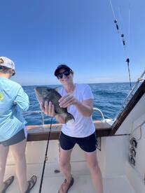A happy angler holding a large fish on a fishing charter, enjoying a day out on the open water.