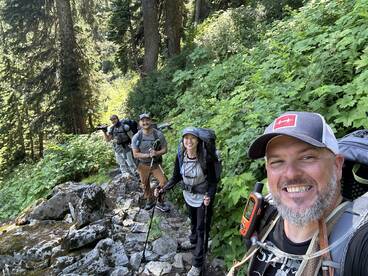 Group of hikers navigating a rocky trail in a lush forest, showcasing their outdoor adventure gear.
