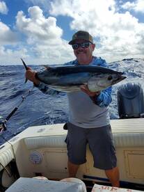 Angler proudly holding a large Tuna while fishing offshore, showcasing a successful day on the water.