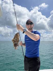 A happy angler holding a freshly caught fish while fishing in open waters, showcasing a successful day on the water.