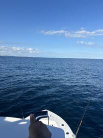 A view from the boat showing the open ocean and fishing gear, with a hand visible on the boat's edge.