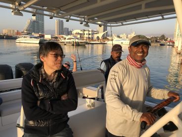 Passengers enjoying a morning on a fishing charter boat, with a scenic marina backdrop and crew members preparing for the day.