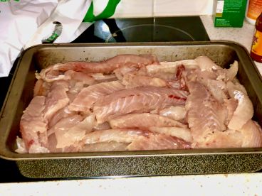 A tray filled with neatly arranged fish fillets, likely prepared for cooking after a successful fishing trip.