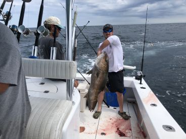 Angler proudly displaying a large Grouper while fishing offshore, showcasing a successful day on the water.