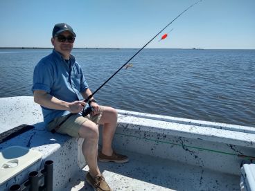 A solo angler fishing from a small boat in calm waters, showcasing a relaxed day on the water.