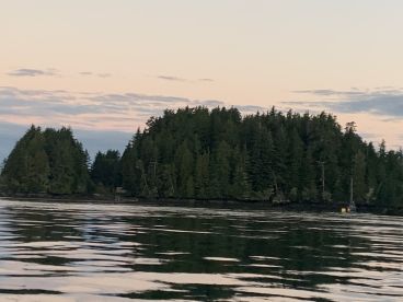 Scenic view of a fishing boat anchored near lush, forested islands at sunset, showcasing the tranquil fishing environment.