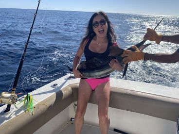 An excited angler holding a large Sailfish while fishing on a sunny day in open waters.