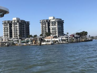 A scenic view of a marina featuring multiple boats and waterfront buildings, showcasing a vibrant fishing environment.