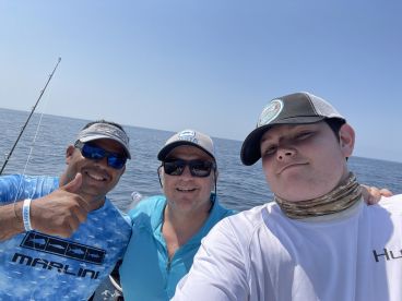 Three anglers posing for a selfie on a fishing boat, enjoying a day out on the water.