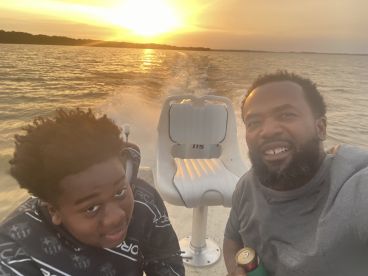 A father and son enjoying a sunset ride on a boat, capturing a memorable moment on the water.