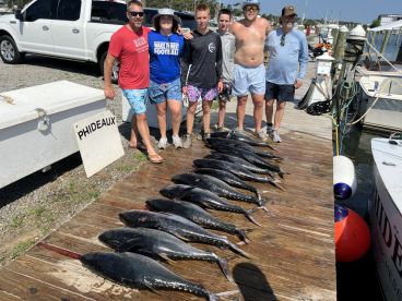 A group of anglers proudly displaying their catch of multiple Blackfin Tuna on the dock after a successful fishing trip.