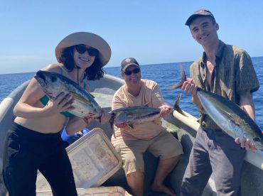 Three anglers proudly displaying their catch of Yellowfin Tuna while enjoying a sunny day on the water.