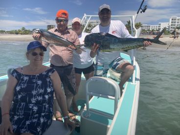 A group of four adults proudly displaying their catch of Mahi Mahi while enjoying a day on the water.