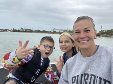 A cheerful group of two children and an adult enjoying a day on the water, showcasing their excitement for fishing.