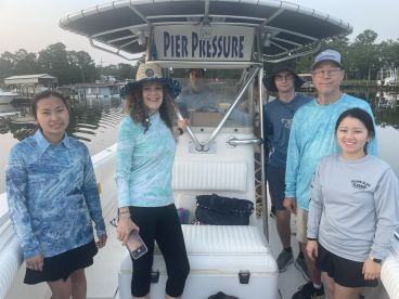 A group of anglers preparing for a fishing trip aboard the 'Pier Pressure' boat, showcasing a comfortable interior setup.