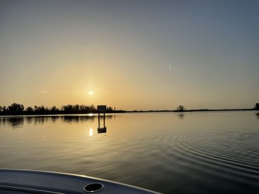 A serene sunset view over calm waters, showcasing the tranquil fishing environment without any visible fishing activity.