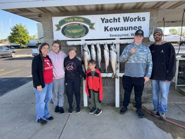A family poses proudly in front of a catch board displaying several Salmon after a successful fishing trip at Yacht Works in Kewaunee, Wisconsin.