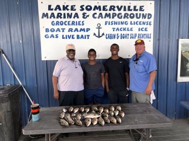 A group of anglers proudly displaying their catch of Crappie and Bass at Lake Somerville Marina, showcasing a successful fishing trip.