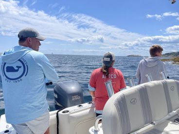 Three anglers enjoying a day of fishing on a boat, casting lines into the open water under a clear blue sky.
