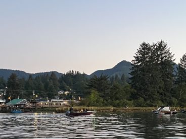 Two boats are visible on a calm waterway surrounded by lush greenery and mountains, showcasing a serene fishing environment.