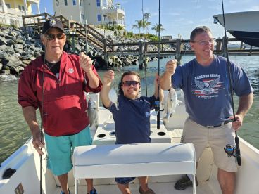 Three anglers proudly displaying their catches, including a notable fish, while enjoying a day of fishing on a boat.