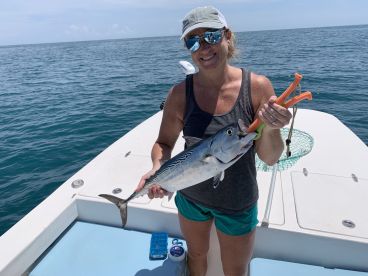 An angler proudly displaying a caught fish while aboard a boat in open waters, showcasing a sunny day fishing experience.