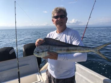 An angler proudly displaying a vibrant Mahi Mahi while fishing offshore, showcasing a beautiful day on the water.
