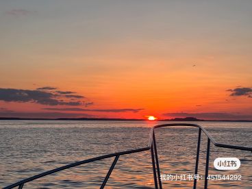 A stunning sunset view from the bow of a boat, showcasing the tranquil waters and distant islands, perfect for evening fishing adventures.